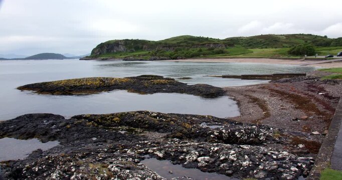 Extra Wide shot of Aonadh Mor and beach of Ganavan Bay at mid tide, black Highland midges at Oban