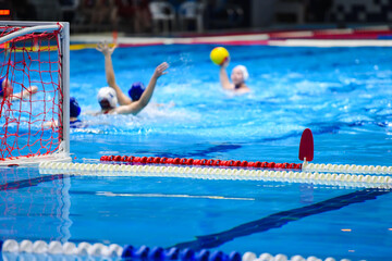 A group of women play water polo in an indoor pool
