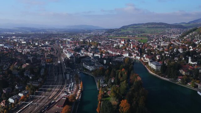 Thun Castle Aare River aerial drone Schloss Thun Thunersee Switzerland Schweiz Europe Autumn Fall pedestrian walkway sunny blue sky clouds yellow birches tree Bernese Oberland backwards pan up motion
