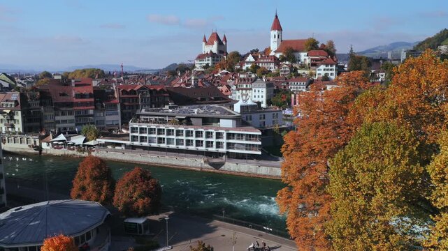 Schloss Thun Flusswelle Aare River sunny blue sky clouds Thun Castle Thunersee Switzerland Schweiz Europe aerial drone Autumn Fall yellow trees pedestrian walk Bernese Oberland circle left motion