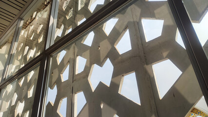 Abstract Islamic background featuring sunlight filtering through a patterned screen, casting geometric shadows on a tiled floor. Minimalist and serene, perfect for Ramadan or Islamic design concepts