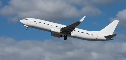 Airplane take off on the blue sky, with white clouds. Aircraft flying on sky background. White passenger jet plane in the blue sky. Low angle view of Airplane flying under blue sky, with white clouds