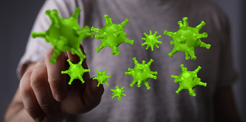 Close-up of hand touching green virus models representing disease spread, health, and global pandemic concepts