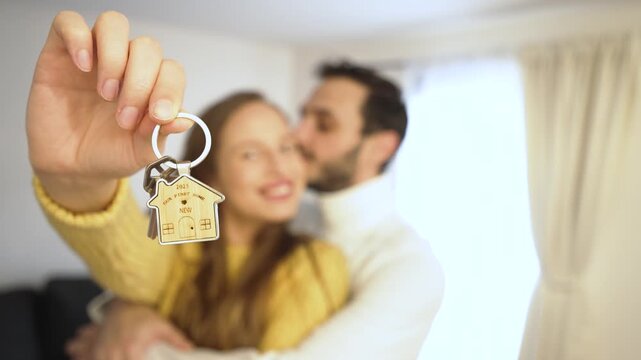 A joyful couple celebrates their new home. The woman proudly holds the key in focus, symbolizing excitement, achievement, and the start of a beautiful chapter together.