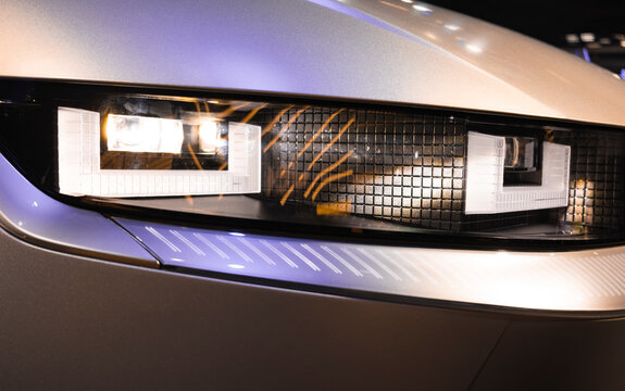 Close-up of an automotive LED headlight, featuring a modern rectangular design, precise lighting, and a sophisticated metallic finish.