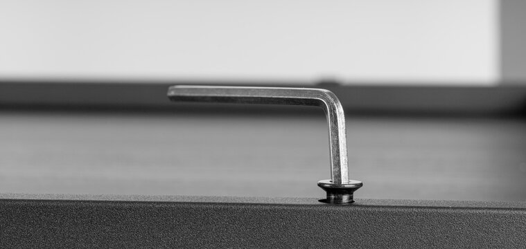 Metal Allen Key Engaged in Hex Screw on Dark Surface