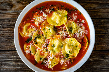 Tomato ravioli soup on wooden table. Top view