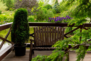 A brown wooden bench next to a pond in a summer park