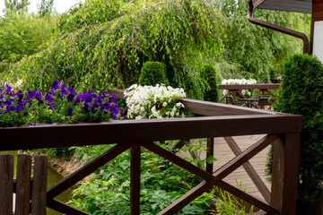 Wooden railings on the terrace next to the pond, decorated with pots with various flowering plants