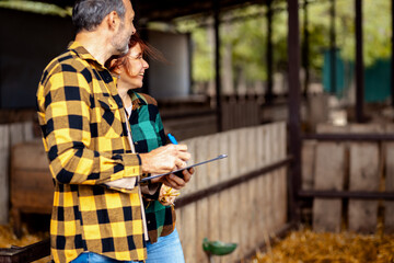 Portrait og male and female farmers on a cow farm.
