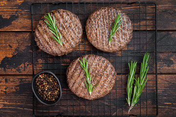 Grilled mixed beef and lamb cutlets with browned crust and savory surface. Top view of cooked meat burger patties on dark wood. © Mironov