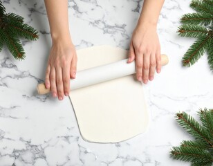 Hands Rolling Out White Dough With Wooden Rolling Pin On Marble Surface Surrounded By Green Pine Needles For Holiday Baking Preparation