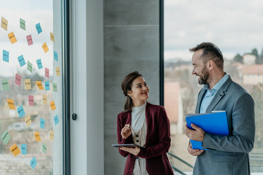 Middle-Aged Man and Young Woman Working in Modern Office with Sticky Notes &ndash; HR and Creative