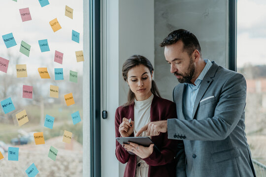 Middle-Aged Man and Young Woman Focused Working in Modern Office with Sticky Notes &ndash; HR Concept