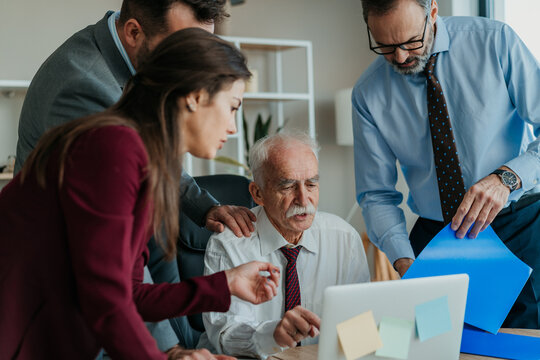 Multi-Generational Business Team Showing Work to Senior Executive in Modern Office &ndash; Mixed Generations