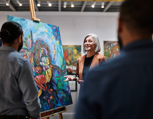An amateur artist stands next to her painting at a local exhibition opening, talking to people viewing the paintings.