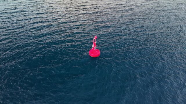 Aerial view of a bright red deep-water navigation buoy equipped with solar panels and sensors. Marine safety infrastructure floating in the sea near Puerto Princesa, Philippines.