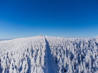 Winter panorama – Aerial view of a snow-covered mountain and mountain station peak under blue sky - Fichtelberg/Erzgebirge