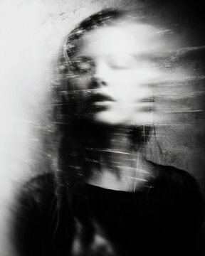 Ghostly young woman experiencing internal psychological turmoil and motion blur