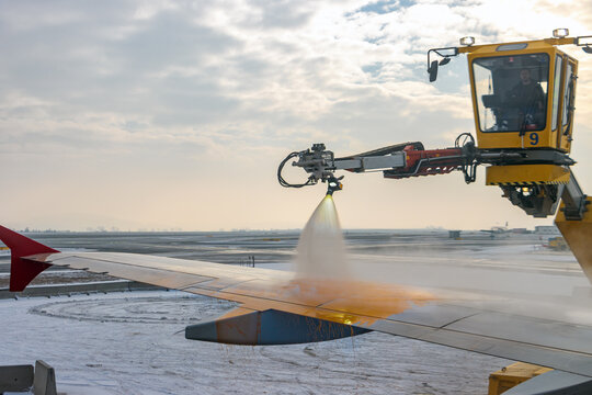 Ground Crew Spraying De-icing Fluid on Airplane Wing During Winter Operations