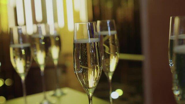 A glass of sparkling wine. A beautiful shade of champagne. Festive mood, smiles, and fun. A beautiful background and close-up of a glass of sparkling wine with fizzing bubbles.