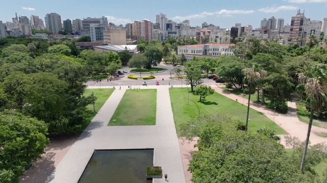 Aerial drone flyover approach view of Water Mirror (Espelho d'Agua) at Redemption Park towards UFRGS University and downtown Porto Alegre, Brazil. 4K 10-bit ProRes.