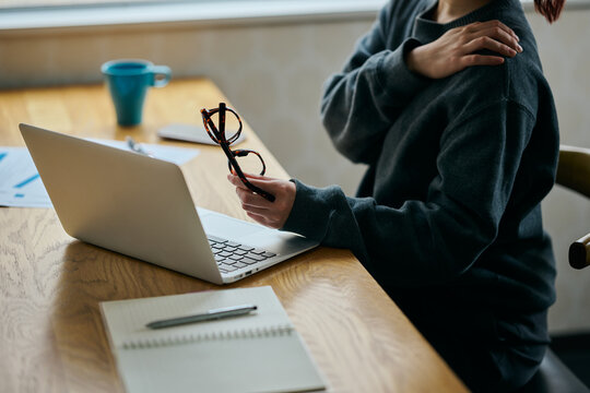 Woman Suffering from Shoulder Pain While Working on Laptop in Home Office