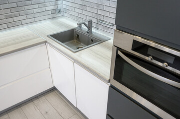 modern kitchen corner with white cabinets, light wood-textured countertop, stainless steel sink and...