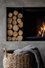 Cozy fireplace ambiance with stacked firewood and a woven basket for a warm interior aesthetic.