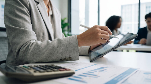 Business professional analyzing financial data on tablet in office meeting - Powered by Adobe