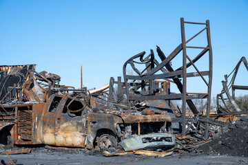Destruction of vehicle and structure after fire at industrial site in morning light