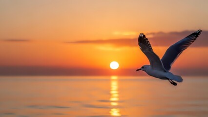 Naklejka premium Seagull flying over calm ocean water during golden sunset with warm orange sky and sun reflection on water surface creating peaceful seascape scene.