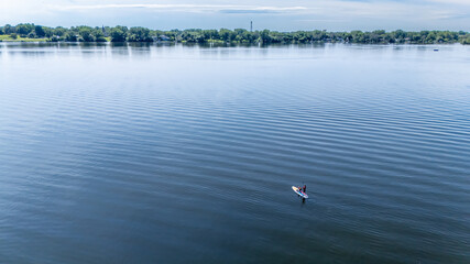 Calm waters at midday with a lone paddleboard gliding smoothly over the serene lake surface