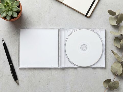 Open CD case with blank disc and notebook on desk