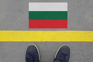 Start on an asphalt road with the Bulgarian flag and legs in shoes. Business, Immigration and Travel in Bulgaria concept