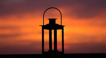 Silhouette of a lantern against a vibrant orange and purple sunset sky with clouds