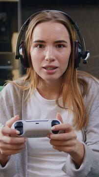 Young blonde woman playing video game in moderm kitchen apartment enjoying indoor activity. Online entertainment and leisure activity concept. Slow motion.