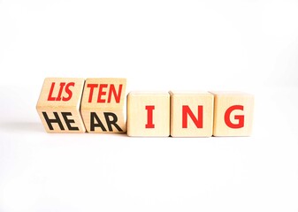 Fototapeta premium Listening or hearing symbol. Concept words Listening to Hearing on beautiful wooden cubes. Beautiful white table white background. Business educational listening or hearing concept. Copy space.