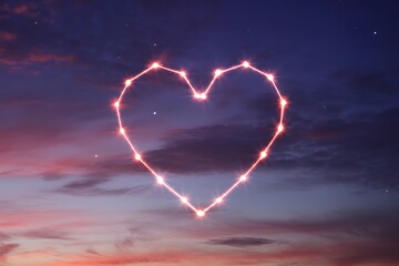 Heart shaped constellation in a starry night sky with pink and purple clouds at sunset