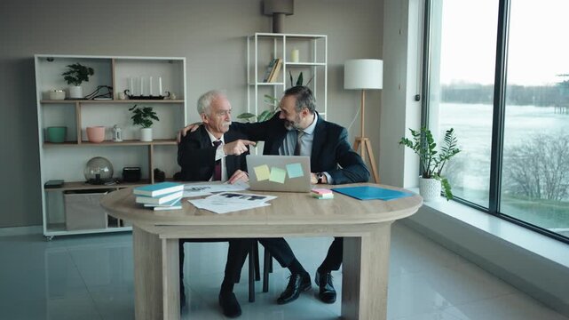Father and Son Businessmen Celebrating Success at Computer in Modern Office &ndash; Senior and Middle Aged Businessmen