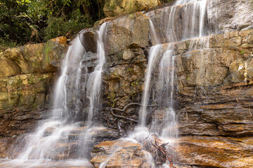 Obraz premium Powerful Bomburu Ella Waterfall Cascading Over Dark Rock in Lush Tropical Forest, Sri Lanka