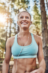 Woman, park and earphones for workout, runner and training in woods for fitness routine. Female person, sports and music or sound for athlete wellness, forest path and ready for exercise or cardio
