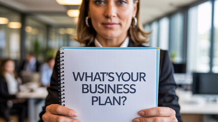 Businesswoman holding notebook with text "WHAT'S YOUR BUSINESS PLAN?" in office setting