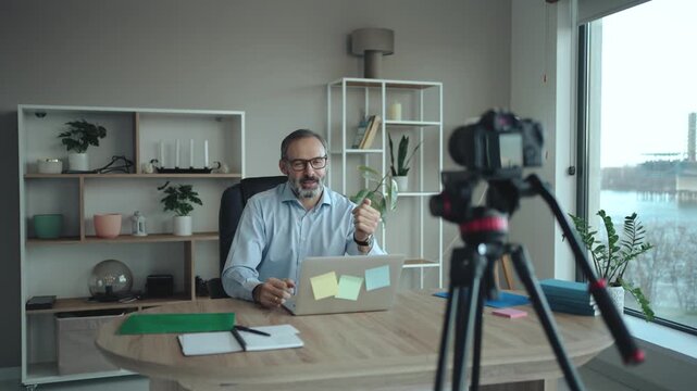 Middle Aged Businessman Recording Vlog in Office with camera