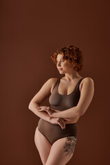 Naklejka premium Young woman embraces body positivity in stylish studio setting with warm tones