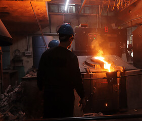 Worker controlling metal melting in furnaces.