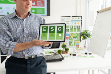 A diverse business team analyzing environmental charts and graphs in a collaborative meeting to create sustainable strategies in a modern office.