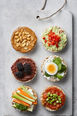 Puffed rice cakes with toppings, appetiser plate on a grey background. Top view