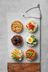 Puffed rice cakes with toppings, appetiser plate on a grey background. Top view