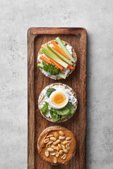 Puffed rice cakes with toppings on a wooden board. Top view